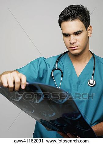 Stock Image - Close-up of a male surgeon examining an MRI scan. Fotosearch