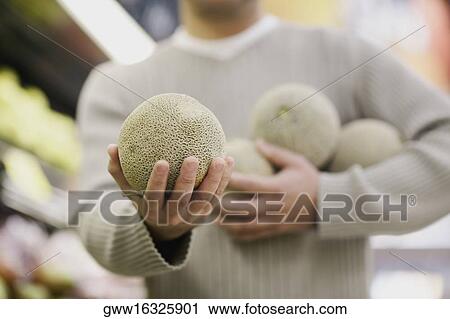 Close-up of a man's hand holding a melon View Large Photo Image Stock Image - Close-up of a man's hand holding a melon. Fotosearch