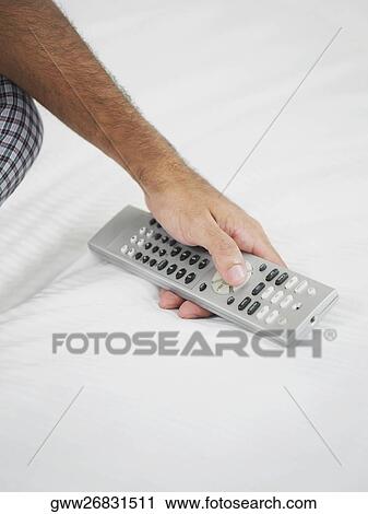 Stock Image - Close-up of a man's hand holding a remote control. Fotosearch