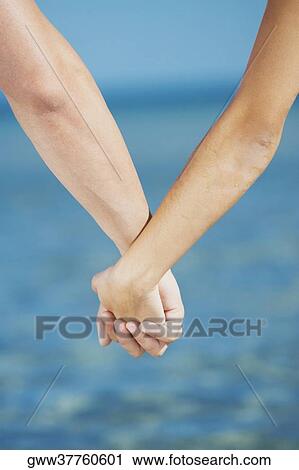 Stock Image - Close-up of a man's hand holding a woman's hand. Fotosearch