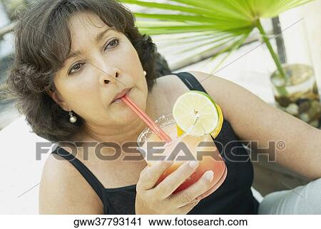 Stock Image - Close-up of a mature woman drinking juice. Fotosearch
