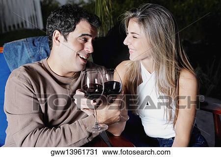 Close-up of a mid adult man and a mid adult woman holding glasses of red wine and smiling View Large Photo Image Stock Image - Close-up of a mid adult man and a mid adult woman holding glasses of red wine and smiling. Fotosearch