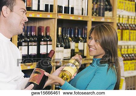 Close-up of a mid adult man and a young woman holding wine bottles in a supermarket View Large Photo Image Stock Image - Close-up of a mid adult man and a young woman holding wine bottles in a supermarket. Fotosearch