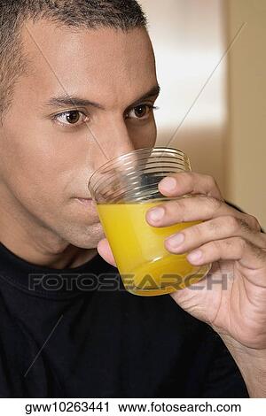 Close-up of a mid adult man drinking orange juice View Large Photo Image Stock Image - Close-up of a mid adult man drinking orange juice. Fotosearch