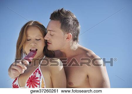 Stock Image - Close-up of a mid adult man feeding ice-cream to a young woman. Fotosearch