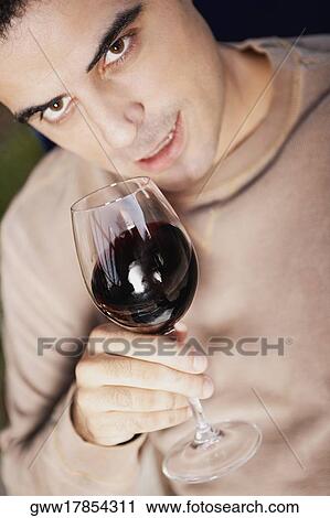 Stock Image - Close-up of a mid adult man holding a glass of red wine. Fotosearch