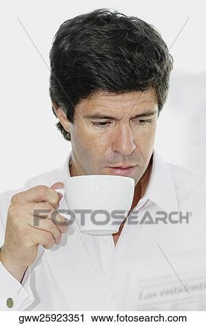 Close-up of a mid adult man holding a tea cup and reading a newspaper View Large Photo Image Stock Image - Close-up of a mid adult man holding a tea cup and reading a newspaper. Fotosearch