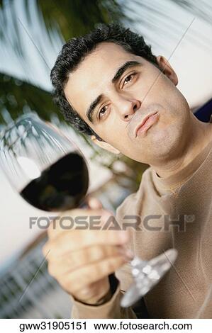 Close-up of a mid adult man holding a glass of red wine and winking View Large Photo Image Stock Image - Close-up of a mid adult man holding a glass of red wine and winking. Fotosearch