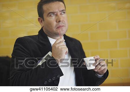Close-up of a mid adult man holding a disposable cup and thinking View Large Photo Image Stock Image - Close-up of a mid adult man holding a disposable cup and thinking. Fotosearch