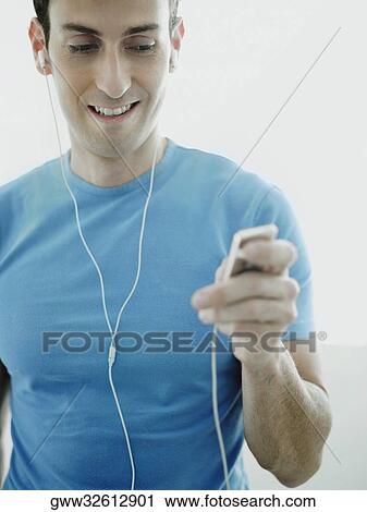 Stock Image - Close-up of a mid adult man listening to an MP3 player. Fotosearch