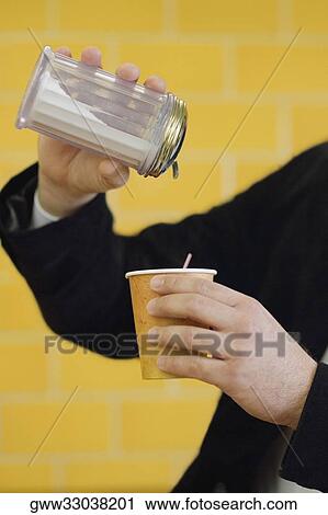 Stock Image - Close-up of a mid adult man pouring milk into a disposable cup. Fotosearch