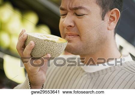Close-up of a mid adult man smelling a cantaloupe View Large Photo Image Stock Image - Close-up of a mid adult man smelling a cantaloupe. Fotosearch
