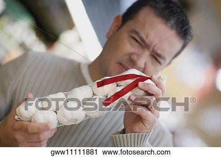 Close-up of a mid adult man smelling garlic View Large Photo Image Stock Image - Close-up of a mid adult man smelling garlic. Fotosearch