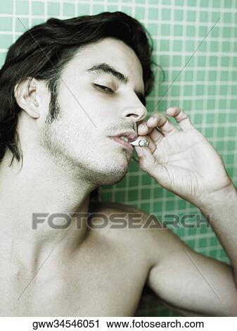 Stock Image - Close-up of a mid adult man smoking. Fotosearch