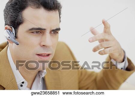 Close-up of a mid adult man wearing a hands free device and gesturing View Large Photo Image Stock Image - Close-up of a mid adult man wearing a hands free device and gesturing. Fotosearch