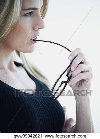 Close-up of a mid adult woman biting a pair of eyeglasses View Large Photo Image Stock Image - Close-up of a mid adult woman biting a pair of eyeglasses. Fotosearch