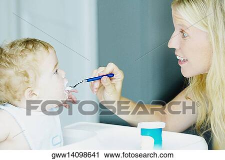Stock Image - Close-up of a mid adult woman feeding her son. Fotosearch