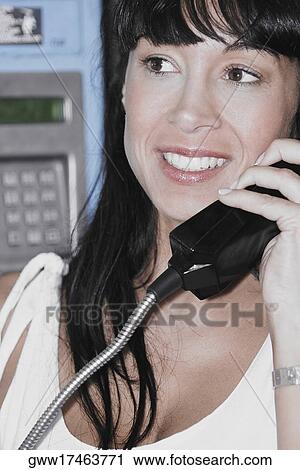 Stock Image - Close-up of a mid adult woman holding a telephone receiver. Fotosearch