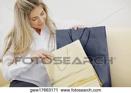 Close-up of a mid adult woman sitting with shopping bags View Large Photo Image Stock Image - Close-up of a mid adult woman sitting with shopping bags. Fotosearch