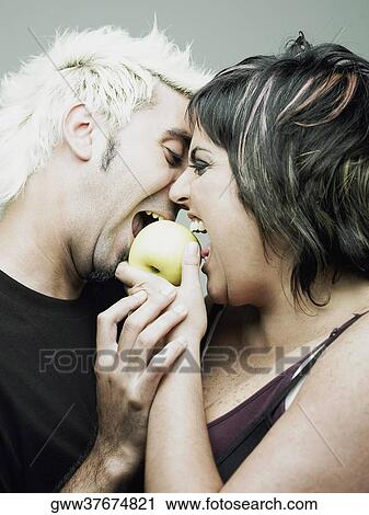 Stock Image - Close-up of a mid adult woman with a young man biting an apple. Fotosearch
