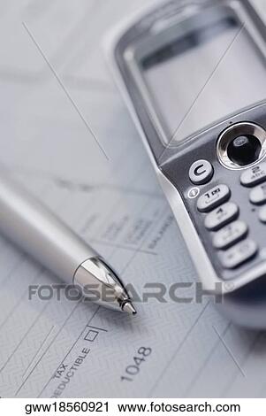 Stock Image - Close-up of a mobile phone and a pen on a document. Fotosearch