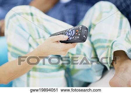 Stock Image - Close-up of a person holding a remote control. Fotosearch