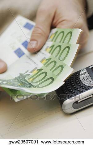 Close-up of a person's hand counting one hundred Euro banknotes View Large Photo Image Stock Image - Close-up of a person's hand counting one hundred Euro banknotes. Fotosearch