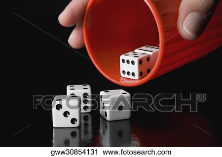 Stock Image - Close-up of a person's hand throwing dice from a cup. Fotosearch