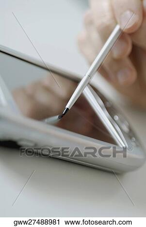 Stock Image - Close-up of a person's hand using a personal data assistant. Fotosearch