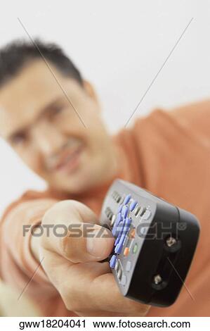 Stock Image - Close-up of a remote control in a mid adult man's hand. Fotosearch