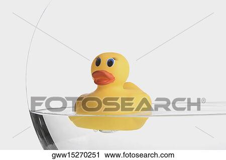 Stock Image - Close-up of a rubber duck floating on water in a jar. Fotosearch