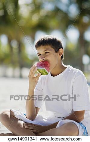 Stock Image - Close-up of a teenage boy eating a slice of watermelon. Fotosearch