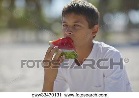 Close-up of a teenage boy eating a slice of watermelon View Large Photo Image Stock Image - Close-up of a teenage boy eating a slice of watermelon. Fotosearch