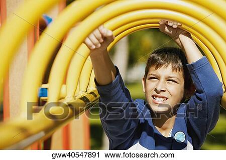 Stock Image - Close-up of a teenage boy on a jungle gym. Fotosearch
