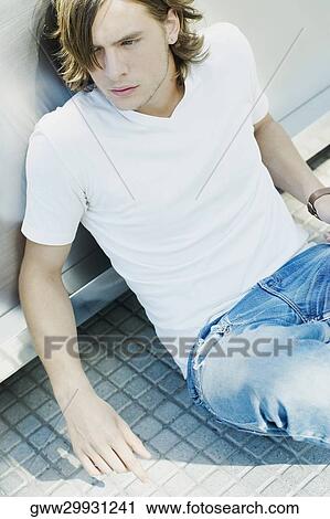 Stock Image - Close-up of a teenage boy sitting on the floor. Fotosearch