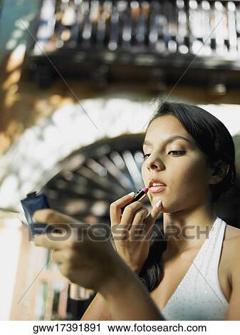 Stock Image - Close-up of a teenage girl applying lipstick on her lips. Fotosearch