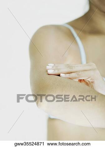 Stock Image - Close-up of a woman applying moisturizer on her arm. Fotosearch