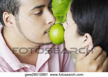 Close-up of a young couple holding a lemon between their mouths View Large Photo Image Stock Image - Close-up of a young couple holding a lemon between their mouths. Fotosearch