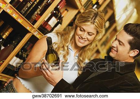 Close-up of a young couple holding a wine bottle in a supermarket View Large Photo Image Stock Image - Close-up of a young couple holding a wine bottle in a supermarket. Fotosearch