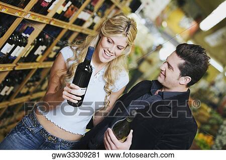 Close-up of a young couple holding wine bottles in a supermarket View Large Photo Image Stock Image - Close-up of a young couple holding wine bottles in a supermarket. Fotosearch
