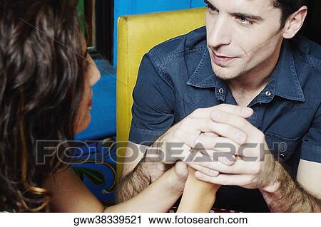Close-up of a young couple sitting and holding each other's hands View Large Photo Image Stock Image - Close-up of a young couple sitting and holding each other's hands. Fotosearch