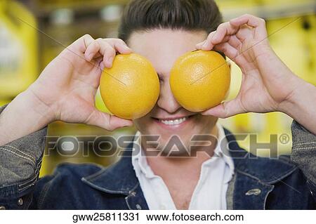 Close-up of a young man covering his eyes with two oranges View Large Photo Image Stock Image - Close-up of a young man covering his eyes with two oranges. Fotosearch