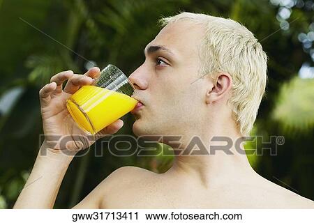 Close-up of a young man drinking a glass of orange juice View Large Photo Image Stock Image - Close-up of a young man drinking a glass of orange juice. Fotosearch