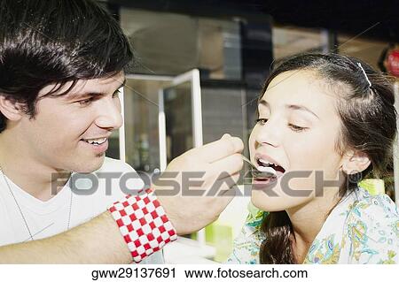 Close-up of a young man feeding ice-cream to a young woman View Large Photo Image Stock Image - Close-up of a young man feeding ice-cream to a young woman. Fotosearch