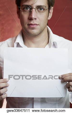 Close-up of a young man holding a blank paper View Large Photo Image Stock Image - Close-up of a young man holding a blank paper. Fotosearch