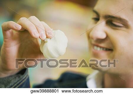 Close-up of a young man holding garlic View Large Photo Image Stock Image - Close-up of a young man holding garlic. Fotosearch