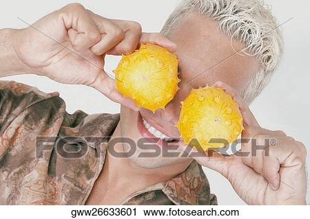 Close-up of a young man holding two kawani fruits on his eyes View Large Photo Image Stock Image - Close-up of a young man holding two kawani fruits on his eyes. Fotosearch
