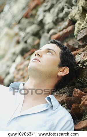 Close-up of a young man leaning against a wall View Large Photo Image Stock Image - Close-up of a young man leaning against a wall. Fotosearch