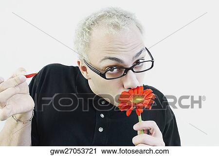 Close-up of a young man smelling a daisy flower View Large Photo Image Stock Image - Close-up of a young man smelling a daisy flower. Fotosearch