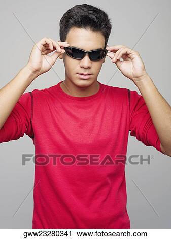 Close-up of a young man wearing sunglasses View Large Photo Image Stock Image - Close-up of a young man wearing sunglasses. Fotosearch